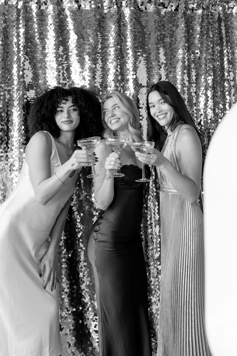 Guests toasting in front of a sequin backdrop