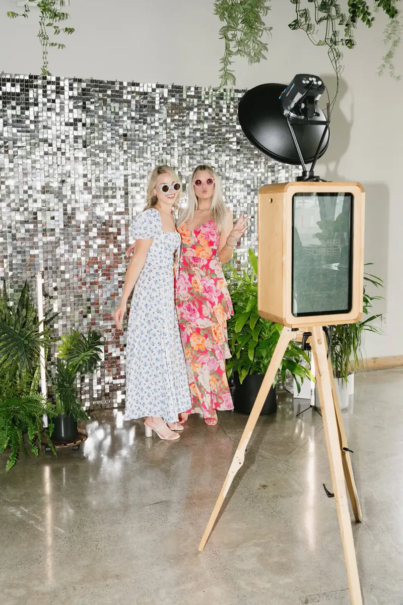 Guests posing at a photo booth against a sequin backdrop