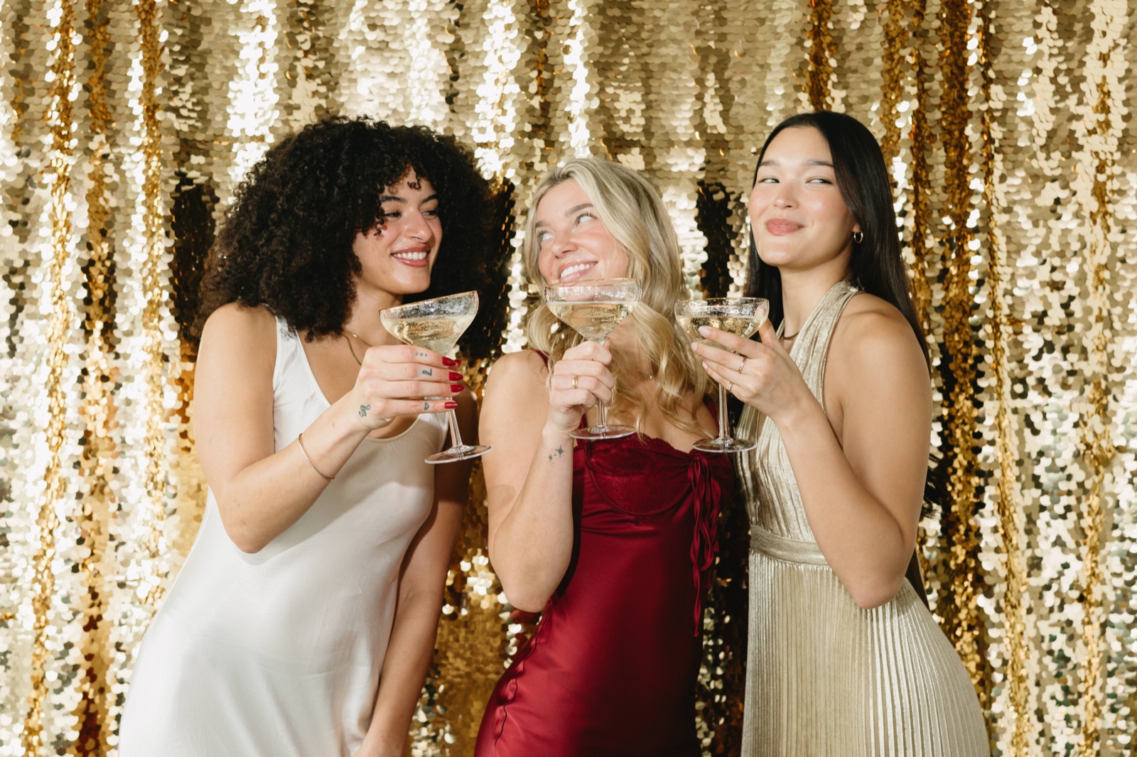 Guests toasting in front of a gold sequin backdrop